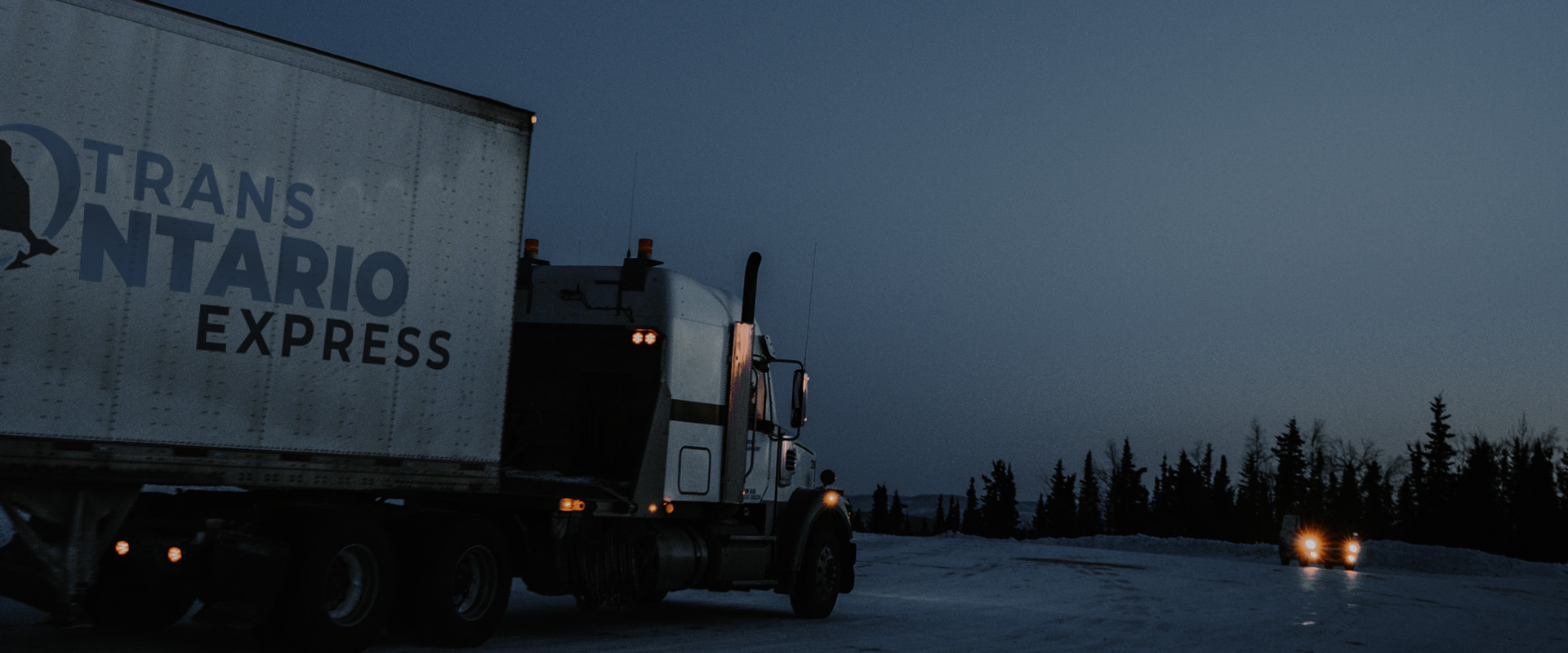 header image for all services and fleet page of a trans ontario tractor trailer on a dark road